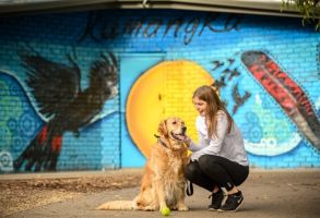 a person and a dog sitting on the ground in front of a wall with graffiti